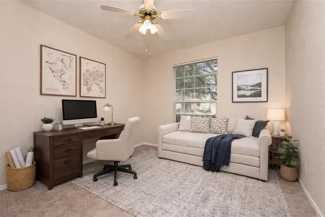 an empty room with a chandelier fan and windows