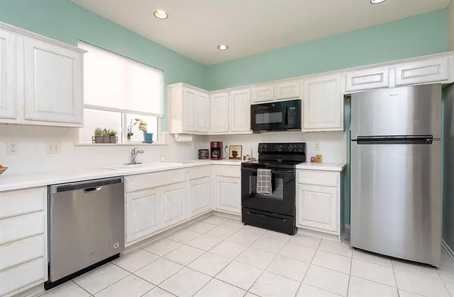 a kitchen with white cabinets and a refrigerator