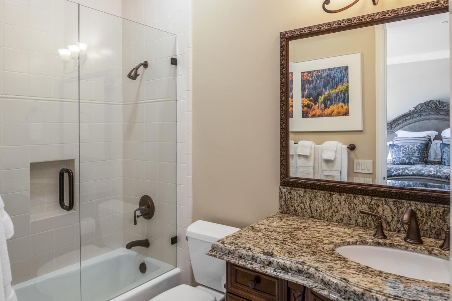 8630 River Meadows Road Carmel, CA 93923 - Photo 24 of 50 a bathroom with a granite countertop sink a mirror a shower and a bathtub