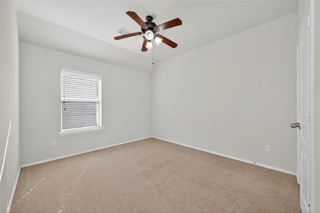 an empty room with a window and a ceiling fan