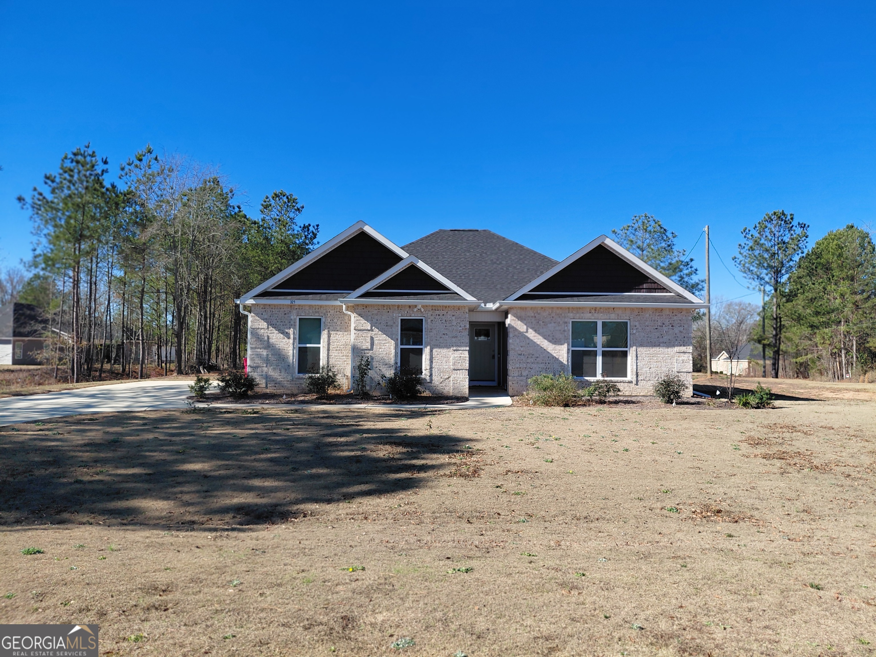 a front view of a house with a dirt yard and a large tree