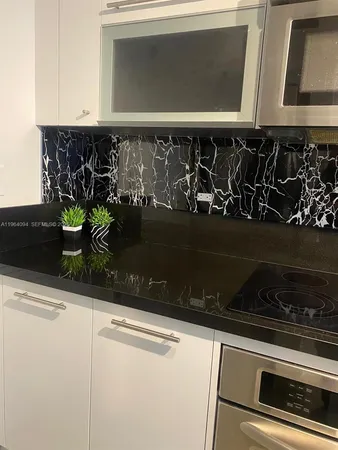 a kitchen with granite countertop white cabinets and black appliances