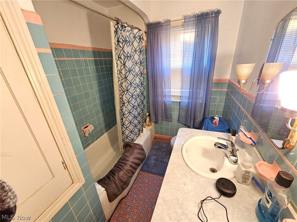 13513 Cedar Road Cleveland, OH 44118 - Photo 22 of 36 Bathroom featuring shower / bathtub combination with curtain, tile floors, sink, and tile walls
