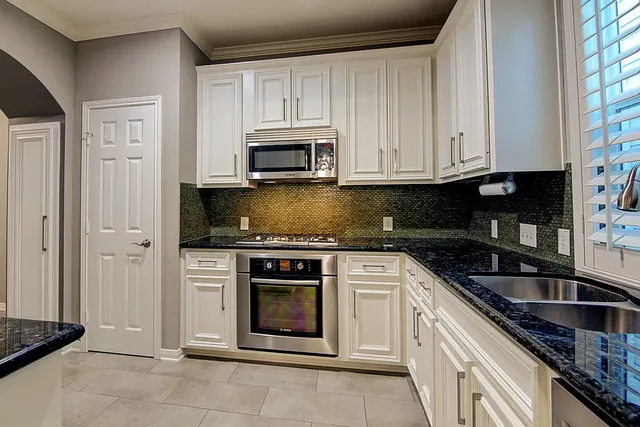 a kitchen with white cabinets stainless steel appliances and sink