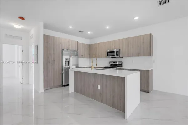 a kitchen with kitchen island white cabinets refrigerator and microwave