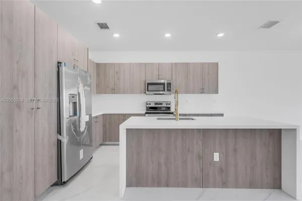 a kitchen with stainless steel appliances granite countertop a refrigerator a stove and a sink