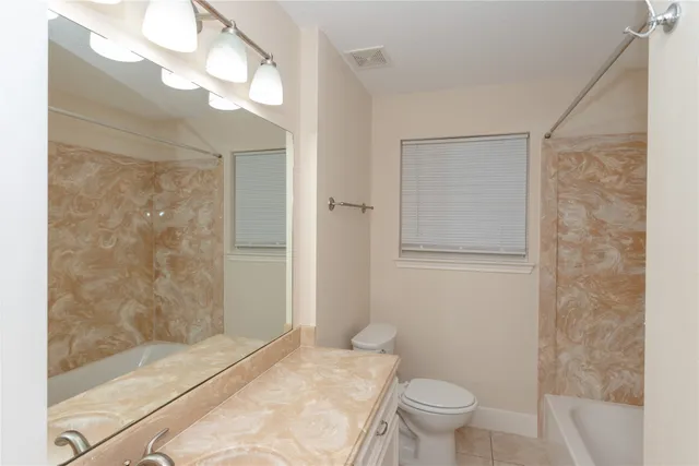 a bathroom with a granite countertop sink a toilet and shower