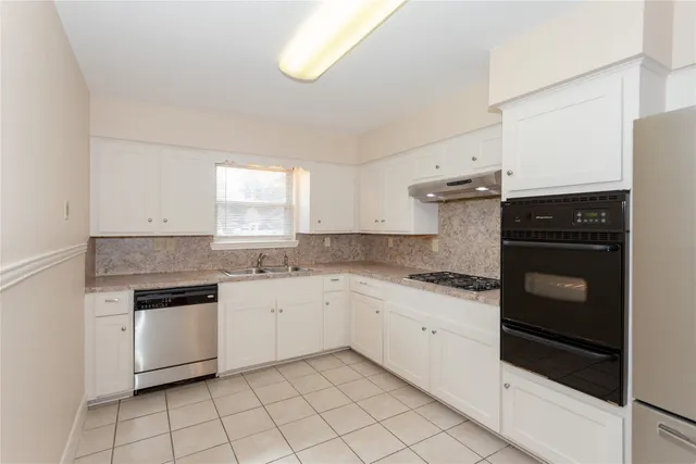 a kitchen with granite countertop white cabinets and white appliances