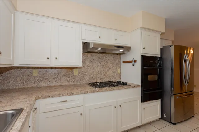 a kitchen with white cabinets and refrigerator