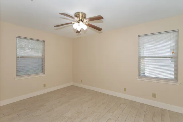 an empty room with windows and fan