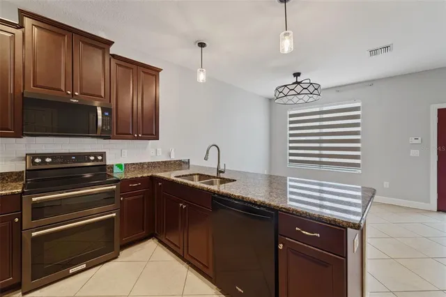 a kitchen with granite countertop a sink stainless steel appliances and cabinets