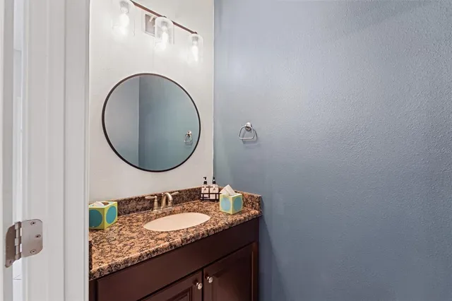 a bathroom with a granite countertop sink a mirror and vanity
