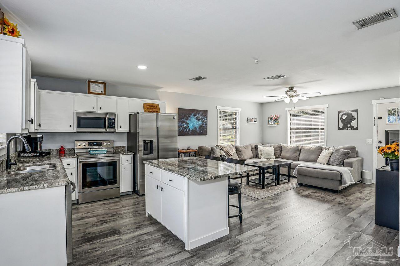 4010 Wyndham Road Century, FL 32535 - Photo 12 of 25 a open kitchen with stainless steel appliances granite countertop a stove top oven a sink dishwasher a dining table and chairs with wooden floor