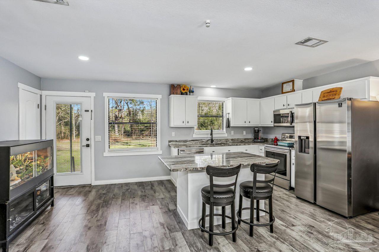 4010 Wyndham Road Century, FL 32535 - Photo 7 of 25 a kitchen with stainless steel appliances a dining table chairs refrigerator and sink