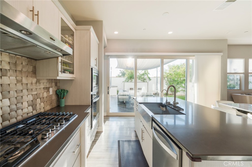 102 Spectacle Irvine, CA 92618 - Photo 11 of 40 a kitchen with kitchen island a large stove a sink a counter space and living room view