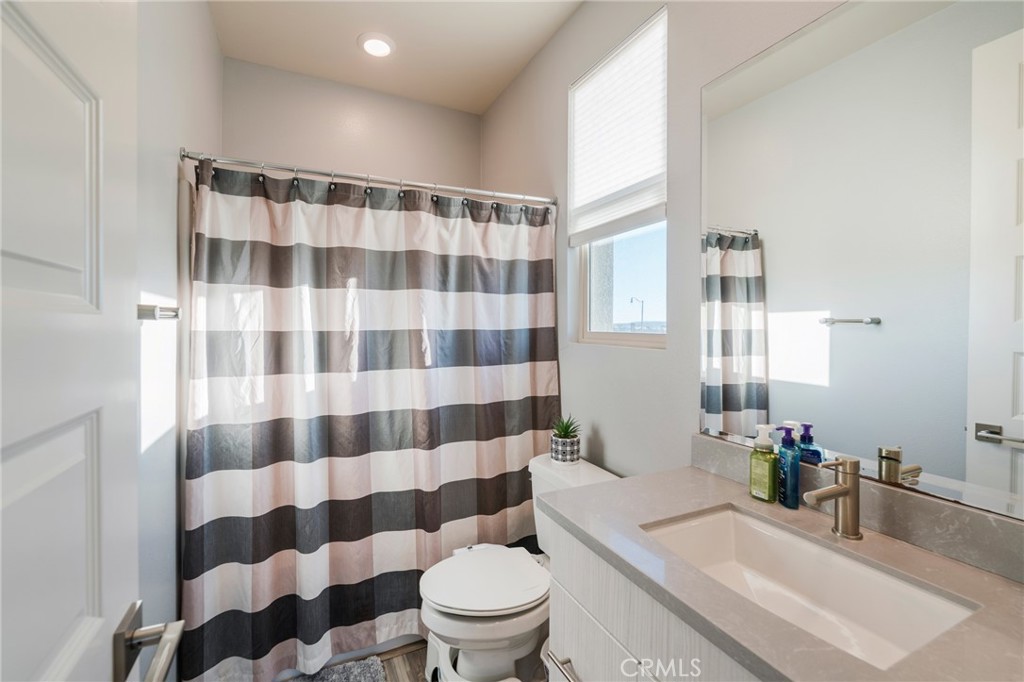 102 Spectacle Irvine, CA 92618 - Photo 28 of 40 a bathroom with a sink a toilet a mirror and shower curtain