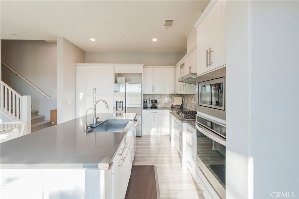 102 Spectacle Irvine, CA 92618 - Photo 10 of 40 a large white kitchen with sink and stainless steel appliances