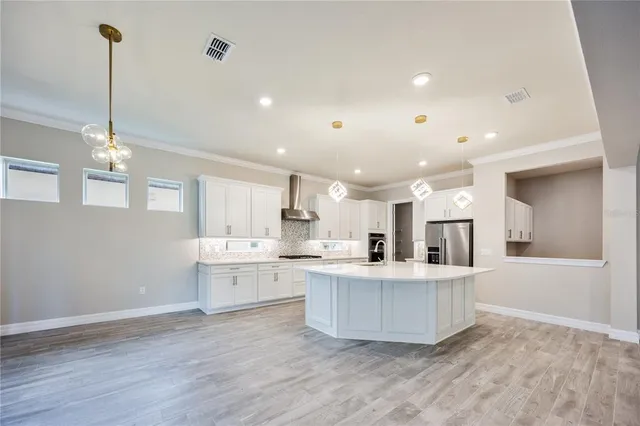 a large kitchen with kitchen island a stove a sink a center island and wooden floor