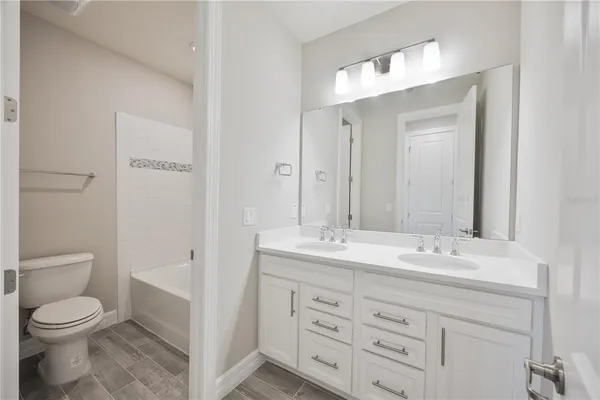 a bathroom with a granite countertop sink toilet a large mirror a vanity and a