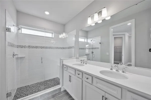 a bathroom with a double vanity sink mirror and shower