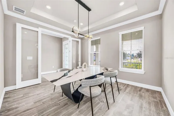a dining room with wooden floor a chandelier a wooden table and chairs