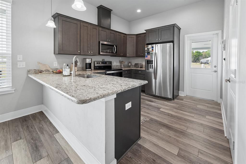 6095 Southwest 82nd Place Trenton, FL 32693 - Photo 23 of 44 a kitchen with stainless steel appliances granite countertop a refrigerator a stove and a wooden floors