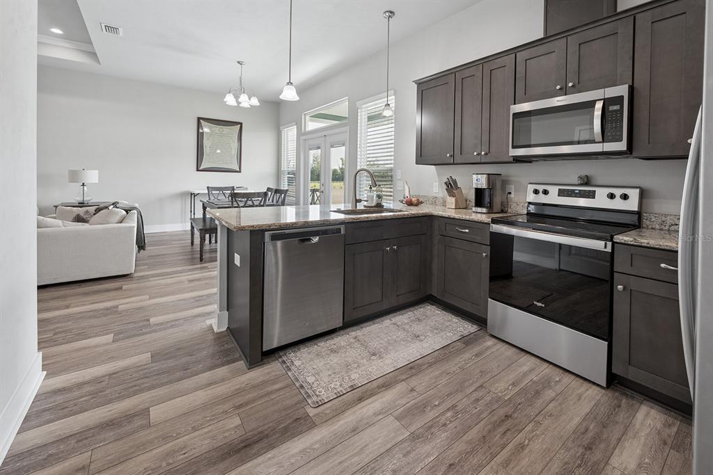 6095 Southwest 82nd Place Trenton, FL 32693 - Photo 25 of 44 a kitchen with stainless steel appliances granite countertop a stove a sink and a microwave