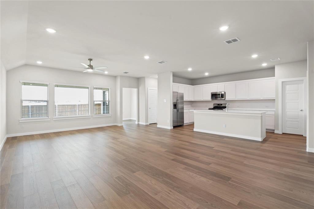 507 Avocet Road Princeton, TX 75407 - Photo 9 of 31 Open-concept design featuring wood-finish flooring, recessed lighting, a ceiling fan, a kitchen island, and stainless steel appliances