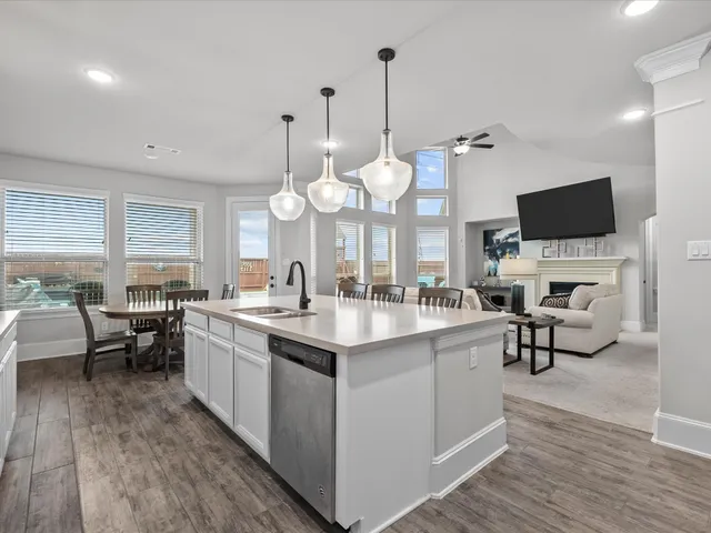 a large white kitchen with a sink and dishwasher a stove with wooden floor