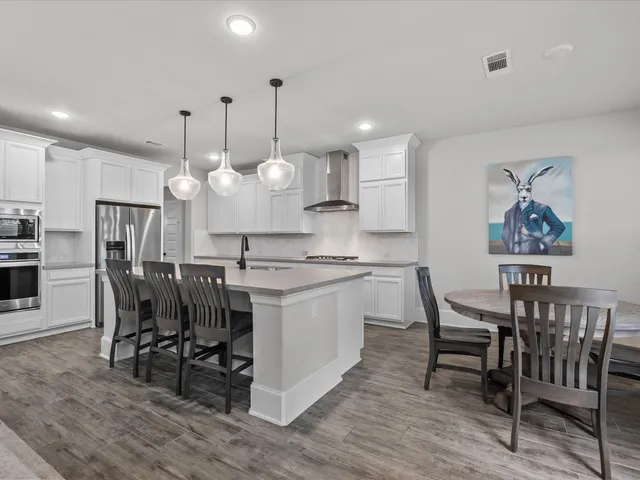 a kitchen with stainless steel appliances kitchen island granite countertop a table chairs and a chandelier