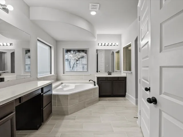 a spacious bathroom with a tub sink shower and mirror
