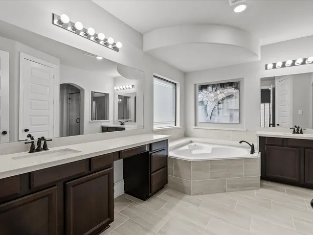 a spacious bathroom with a bathtub double sink mirror and