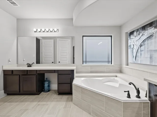 a spacious bathroom with a tub sink and mirror
