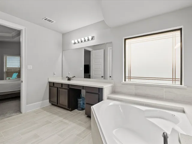a spacious bathroom with a tub double sink and mirror