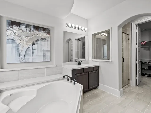 a spacious bathroom with a tub sink and mirror