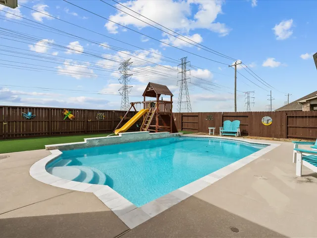 a view of a swimming pool with a yard and furniture