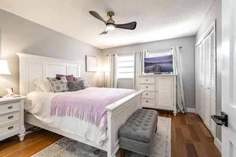 a spacious bedroom with a bed and a flat tv screen on dresser