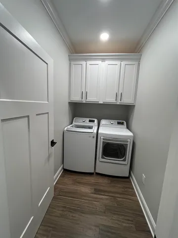 a utility room with wooden floor washer and dryer