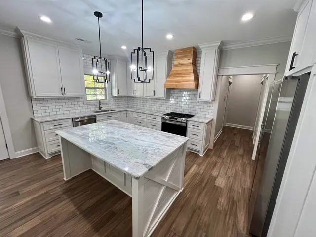 a kitchen with kitchen island a counter space a sink appliances and cabinets