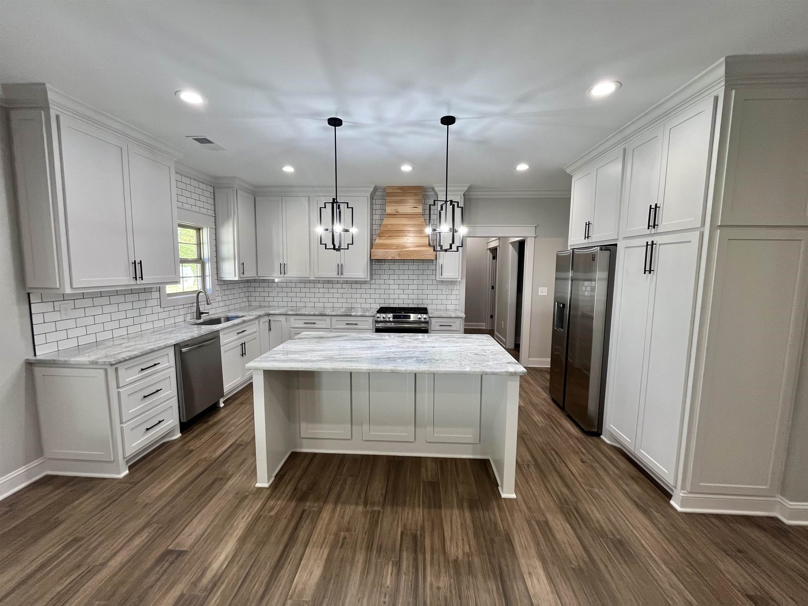 110 RB Drive Savannah, TN 38372 - Photo 9 of 18 a large kitchen with granite countertop a large stove a sink dishwasher a refrigerator and white cabinets with wooden floor