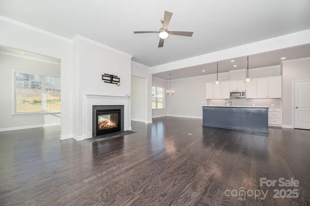 a view of a kitchen with furniture a ceiling fan and wooden floor