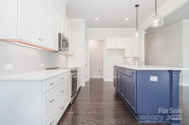 a kitchen with kitchen island granite countertop a sink and a refrigerator