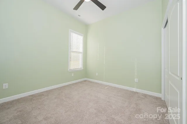 an empty room with ceiling fan and window