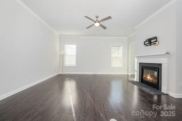 a view of an empty room with wooden floor fireplace and a window
