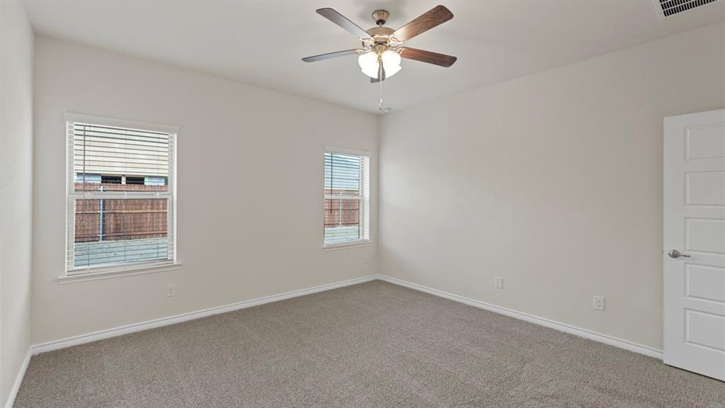 447 Epiphany Lane Lavon, TX 75166 - Photo 17 of 31 Carpeted interior room with white walls, two windows featuring horizontal blinds, and a ceiling fan with integrated lighting
