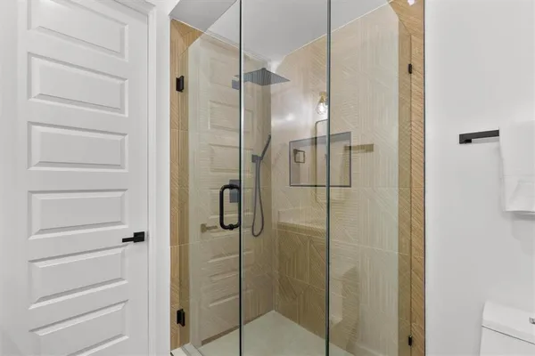 a bathroom with a granite countertop sink a toilet a mirror and shower