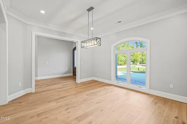 a view of an empty room with window and chandelier
