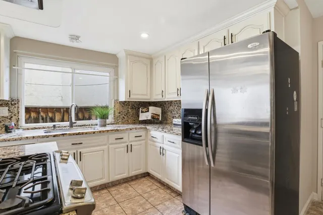 a kitchen with stainless steel appliances kitchen island granite countertop a stove and white cabinets