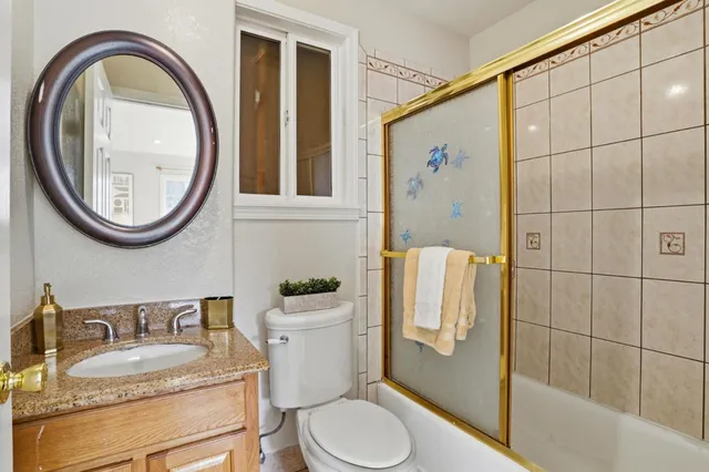a bathroom with a granite countertop toilet sink and mirror