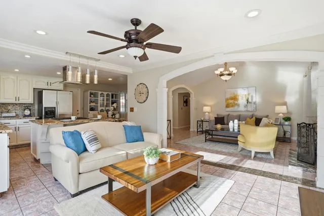 a living room with furniture kitchen view and a chandelier